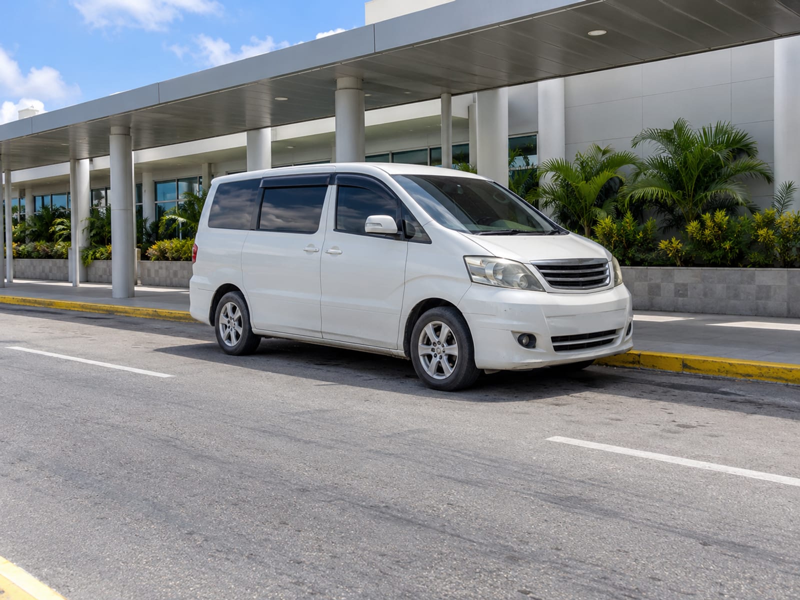 A minivan parked outside an airport terminal