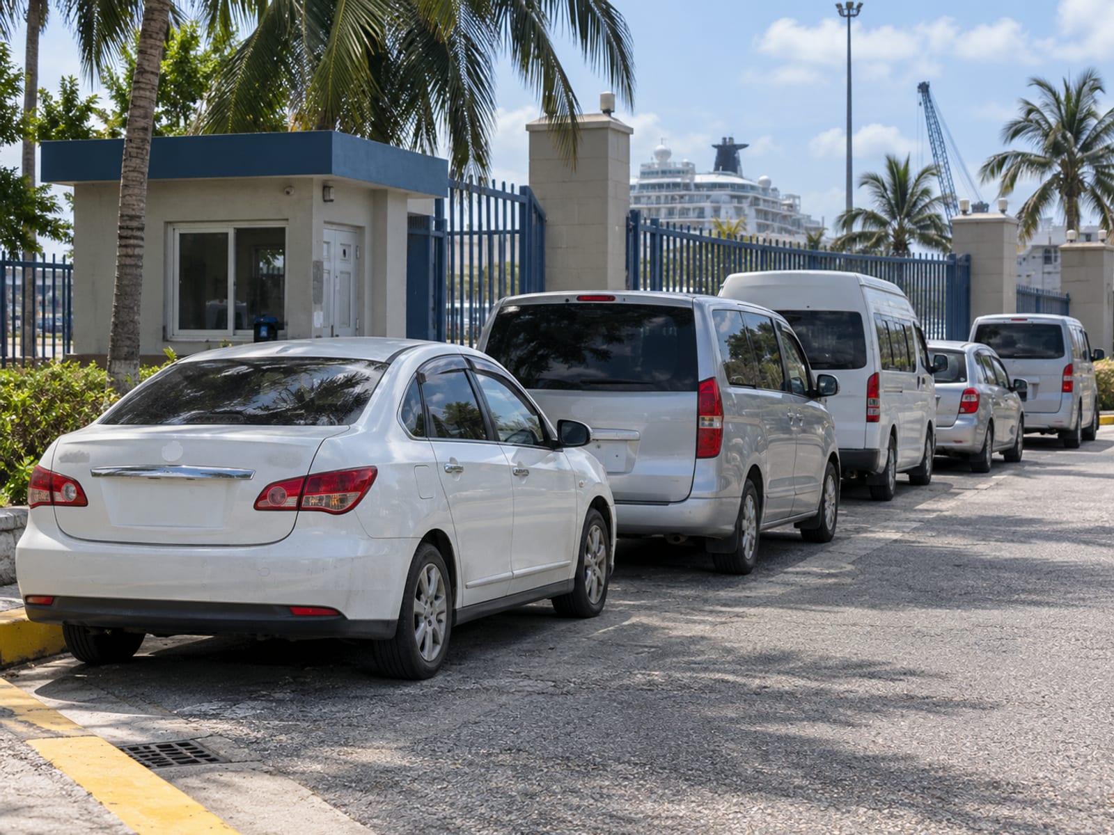 A row of taxis and tour vans waiting outside a cruise port gate