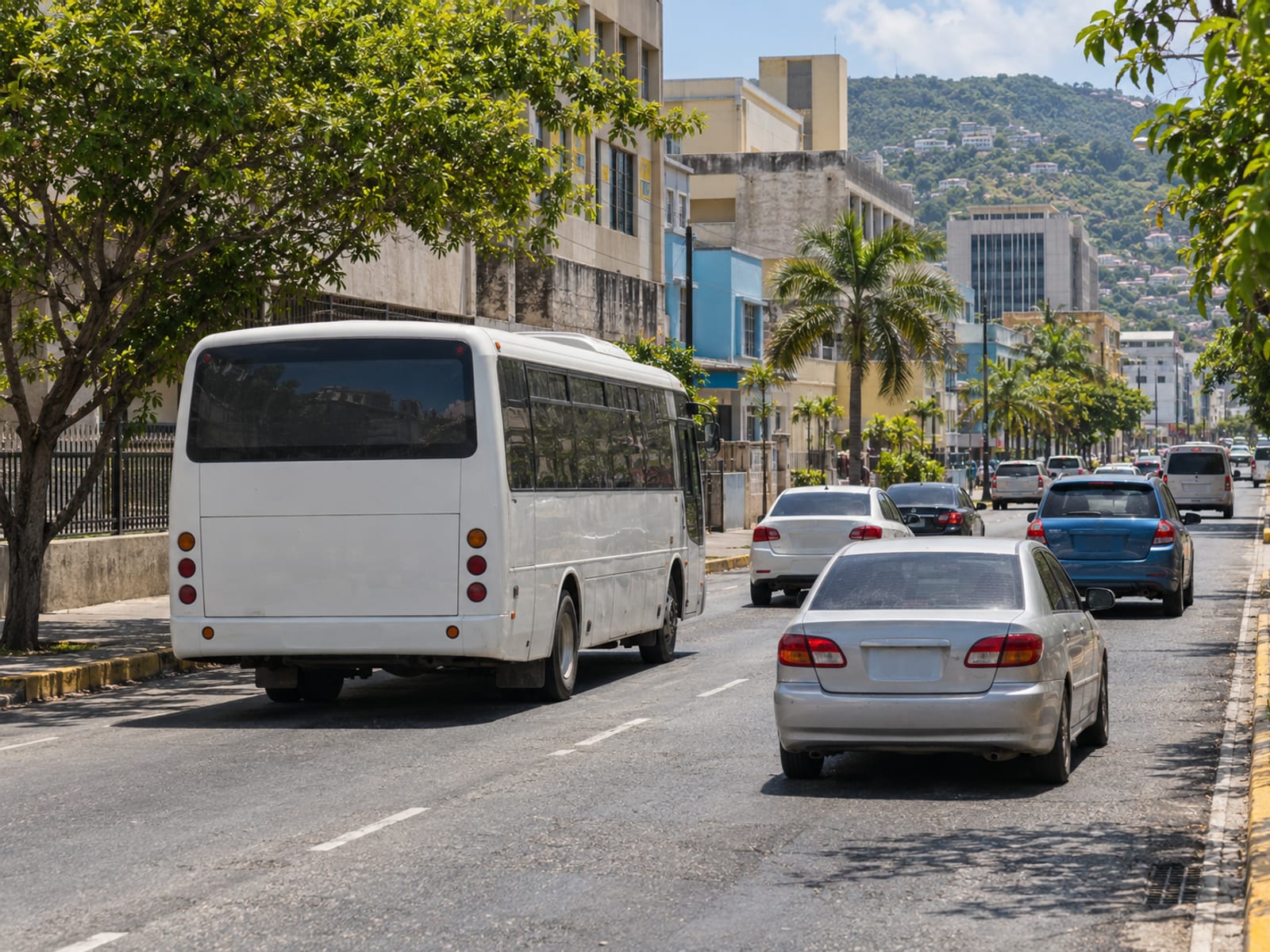 A busy street in a Caribbean city with a bus and taxis in traffic