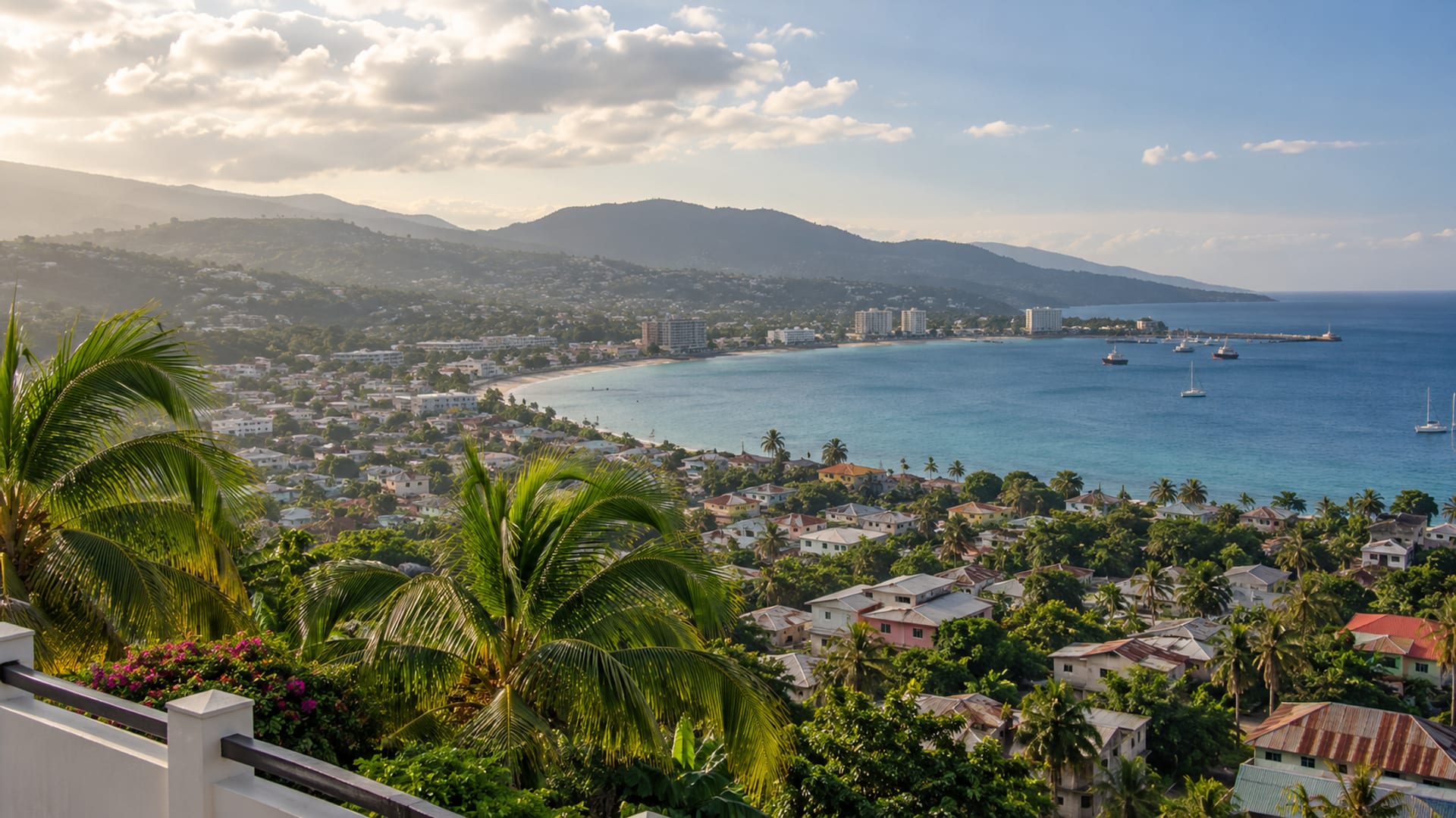 A wide bay curving past a hillside city with the sea glowing in late-afternoon light