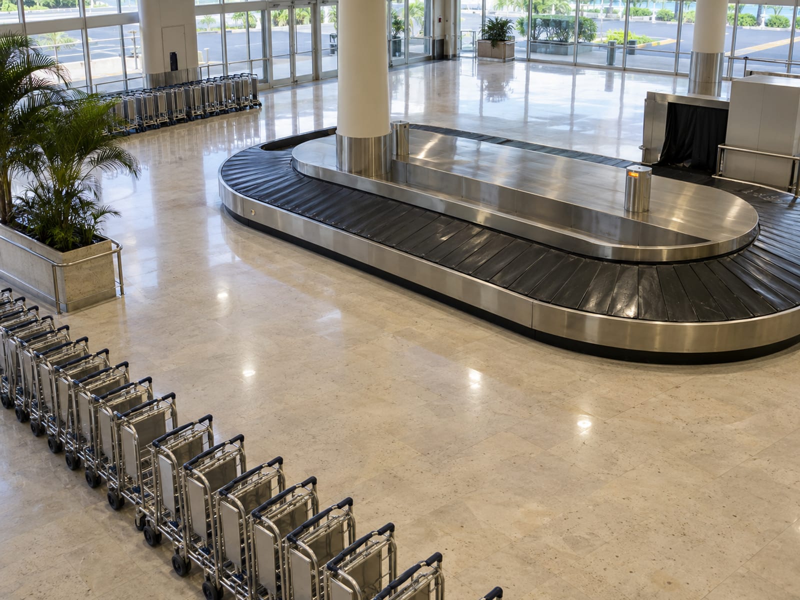 An airport arrivals hall with travellers and luggage trolleys