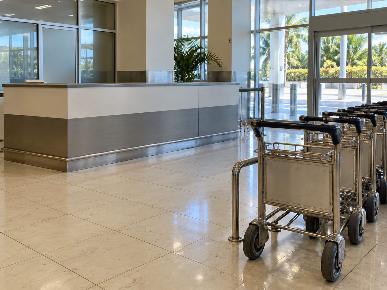 An airport arrivals hall with a taxi desk and luggage trolleys waiting