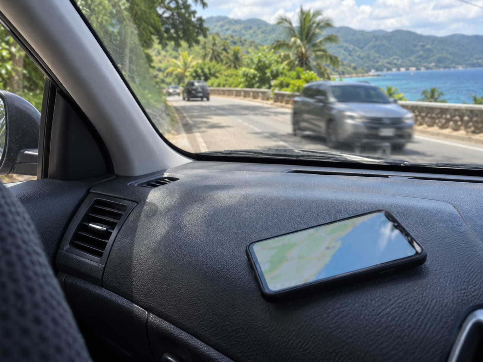 A phone showing a map beside a road with passing traffic