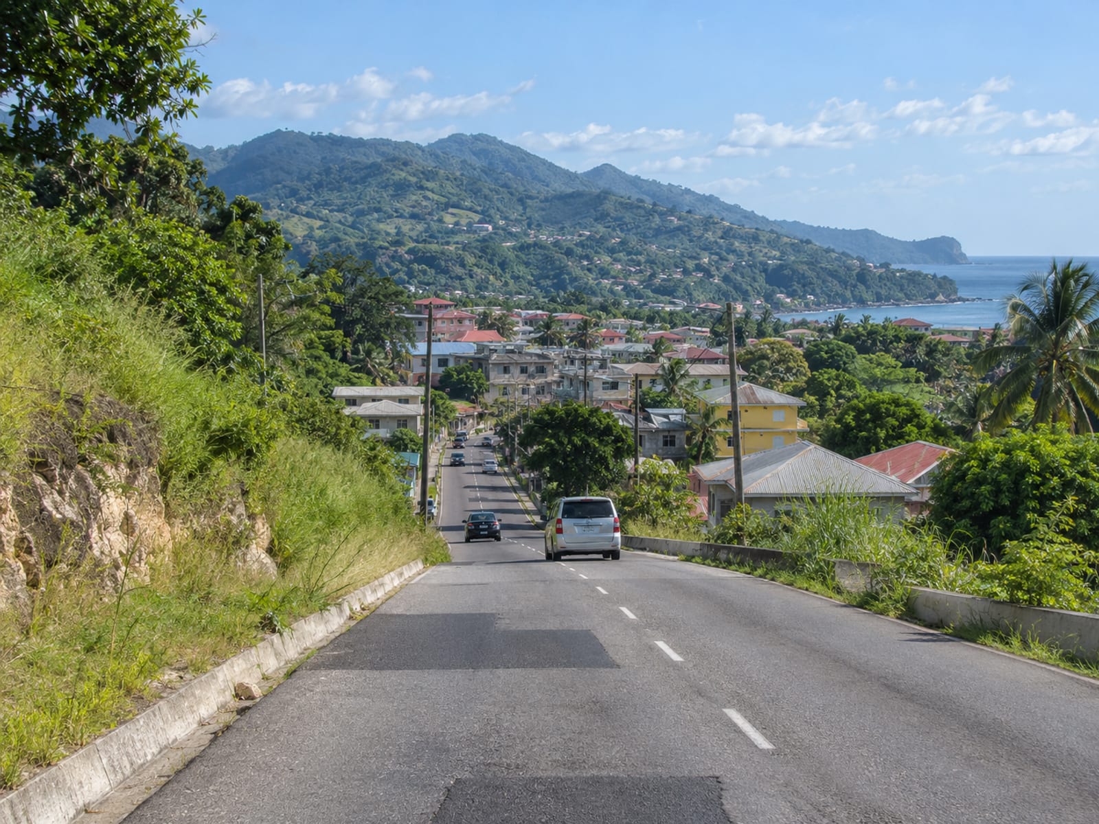 A road leading into a Jamaican town between green hills