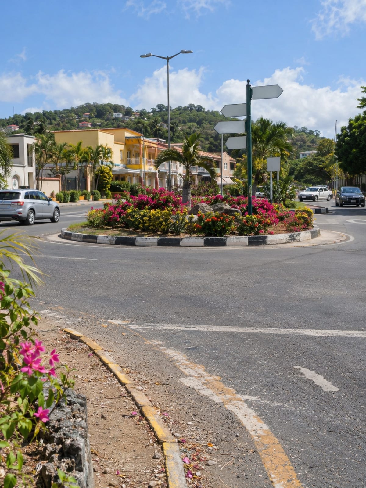A small town roundabout planted with flowers and a few cars