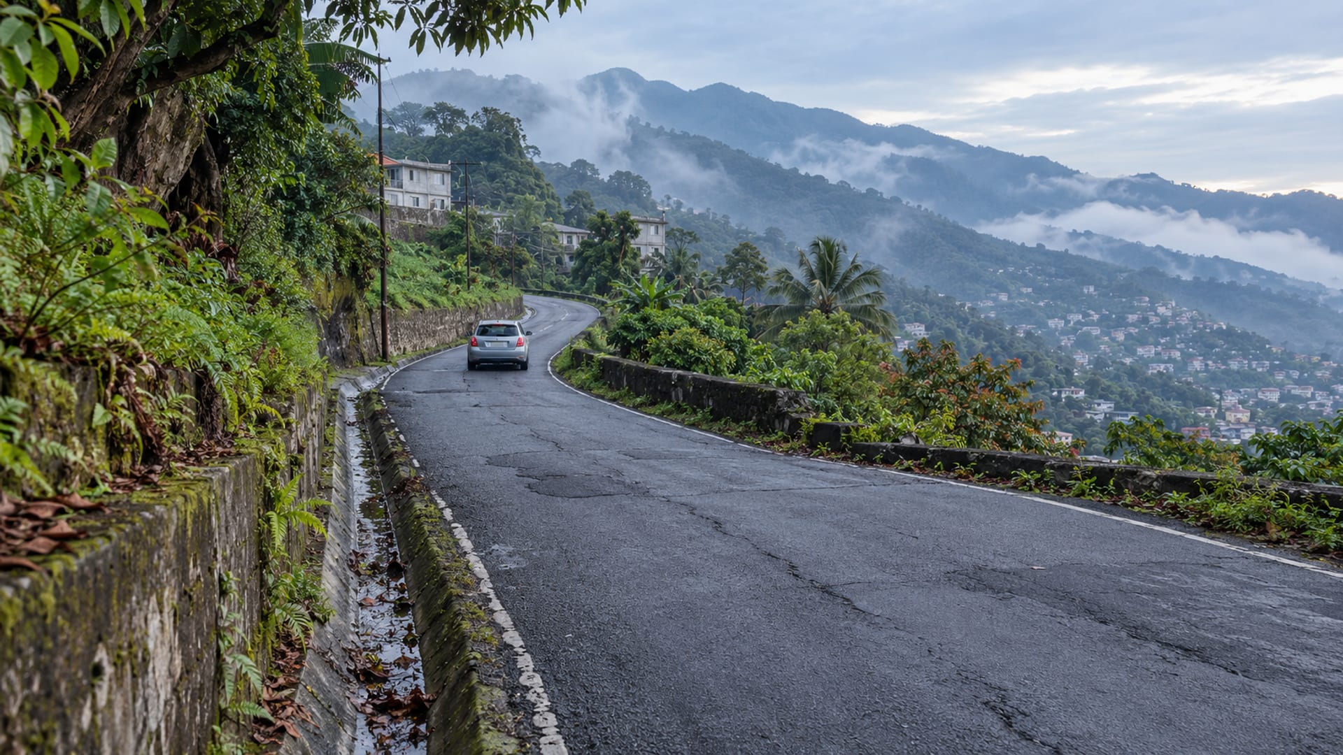 A road climbing from the city into misty mountain foothills