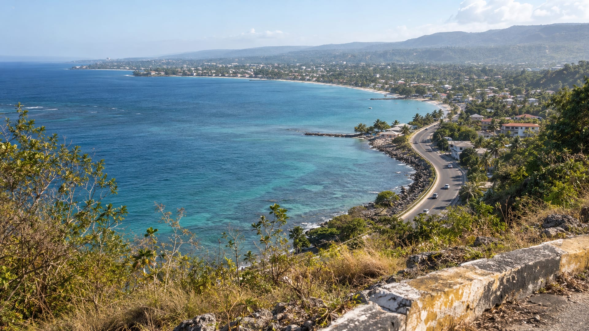 A hillside view over a wide bay with a coastal highway along the shore