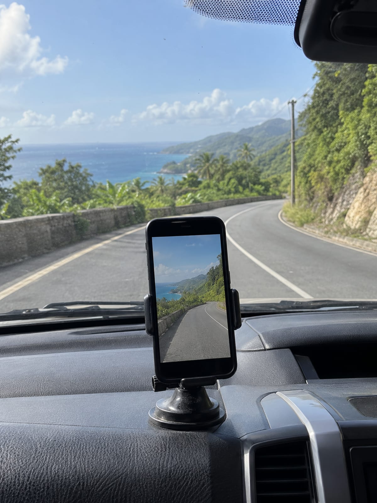 A phone in a dashboard mount recording a winding hill road