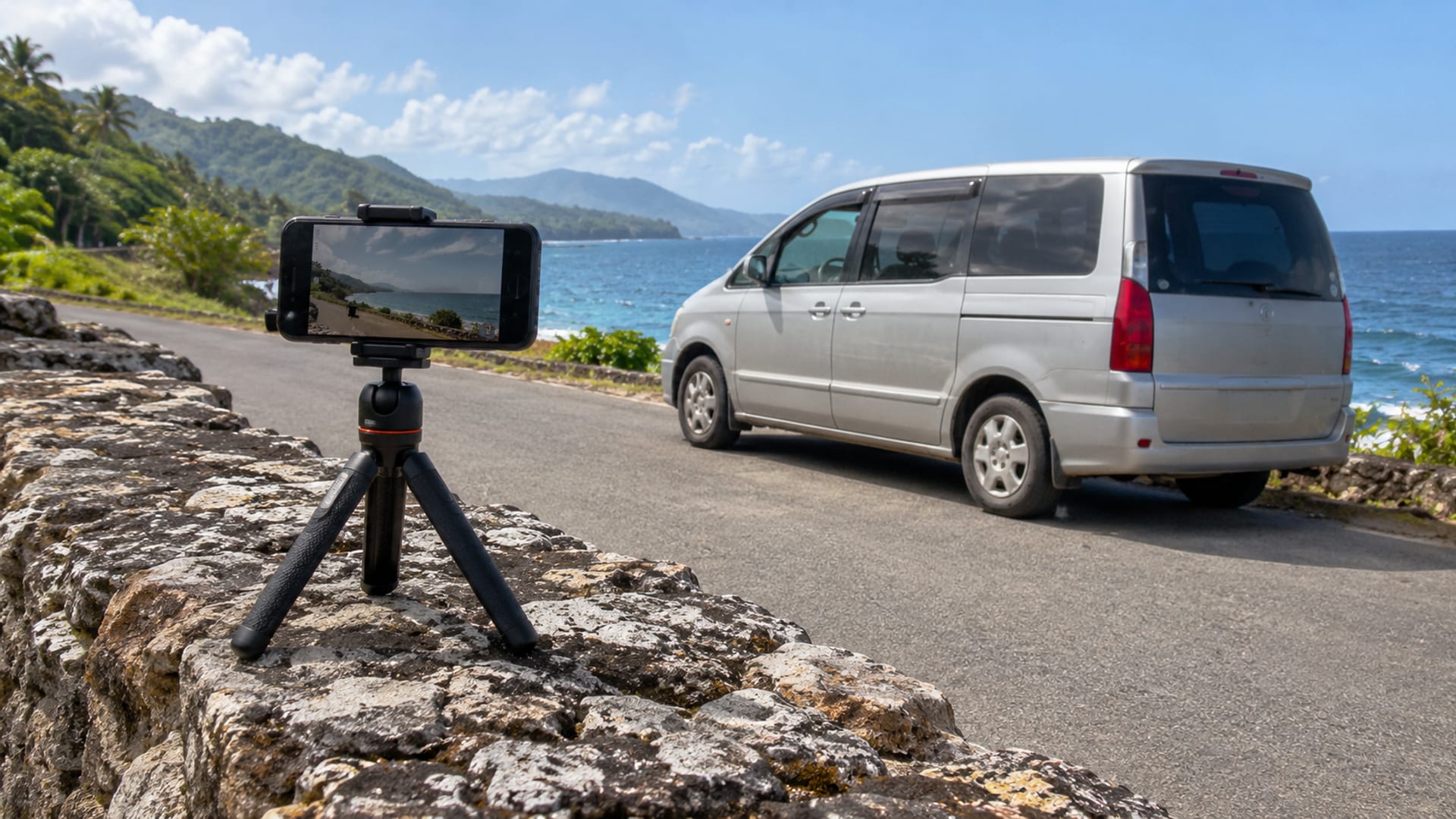 A phone on a tripod filming a minivan parked by the sea